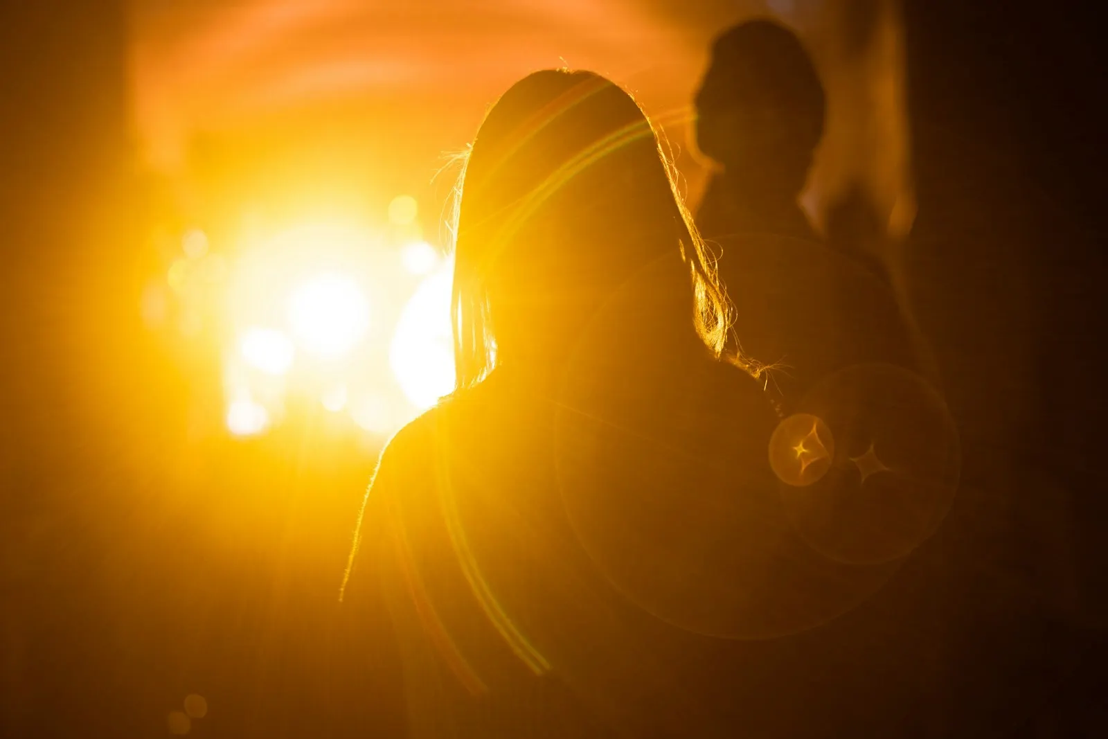Silhouette féminine baignée d'une lumière dorée, entre attente et anticipation