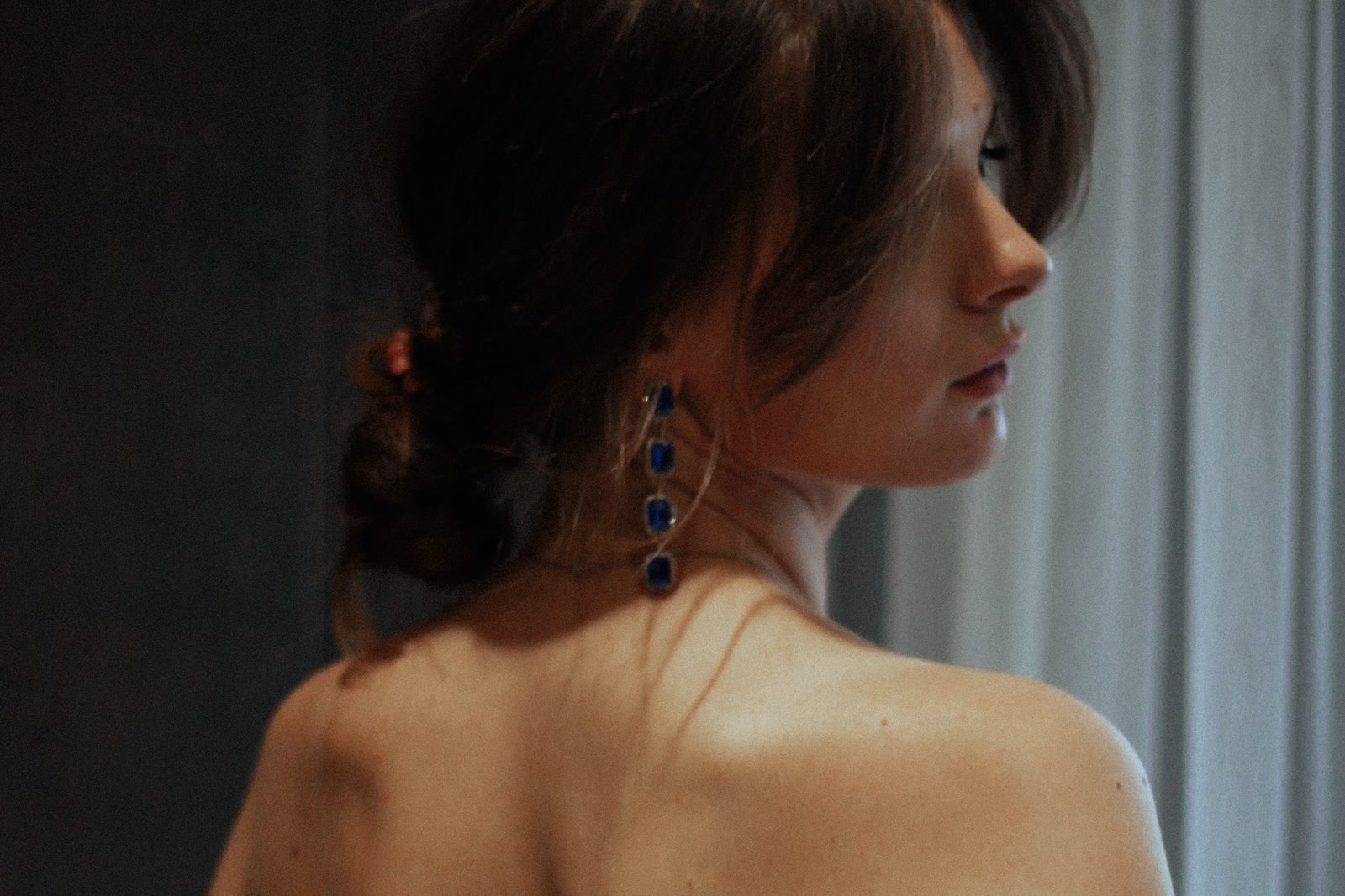 Détail d'une boucle d'oreille pendante sur une robe noire à épaules dénudées