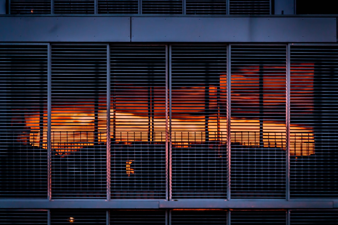 the sun is setting behind the blinds of a building