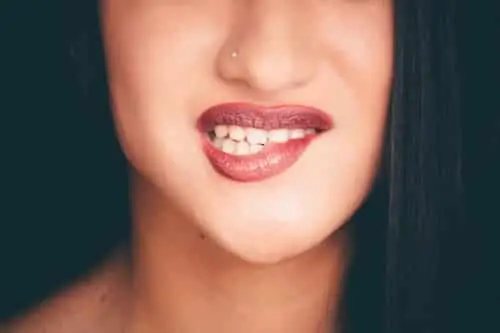 Gros plan sur la bouche d’une femme au rouge à lèvres foncé, piercing au nez