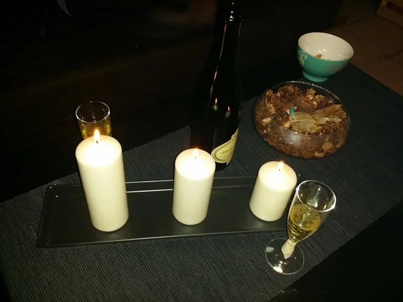 Table basse dressée à la bougie : trois bougies, bouteille de vin, coupe de champagne et amuse-bouches