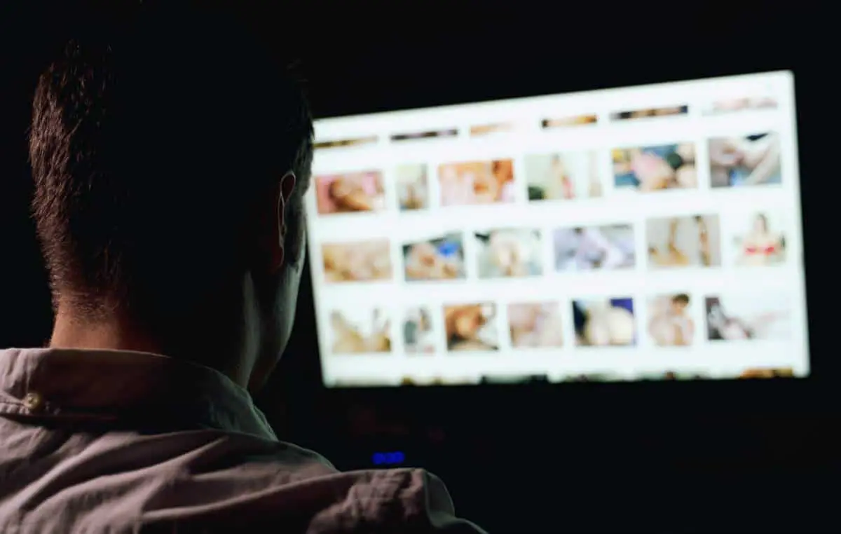 Article suivant : Homme de dos face à un écran affichant une grille de vignettes vidéo, dans une pièce sombre