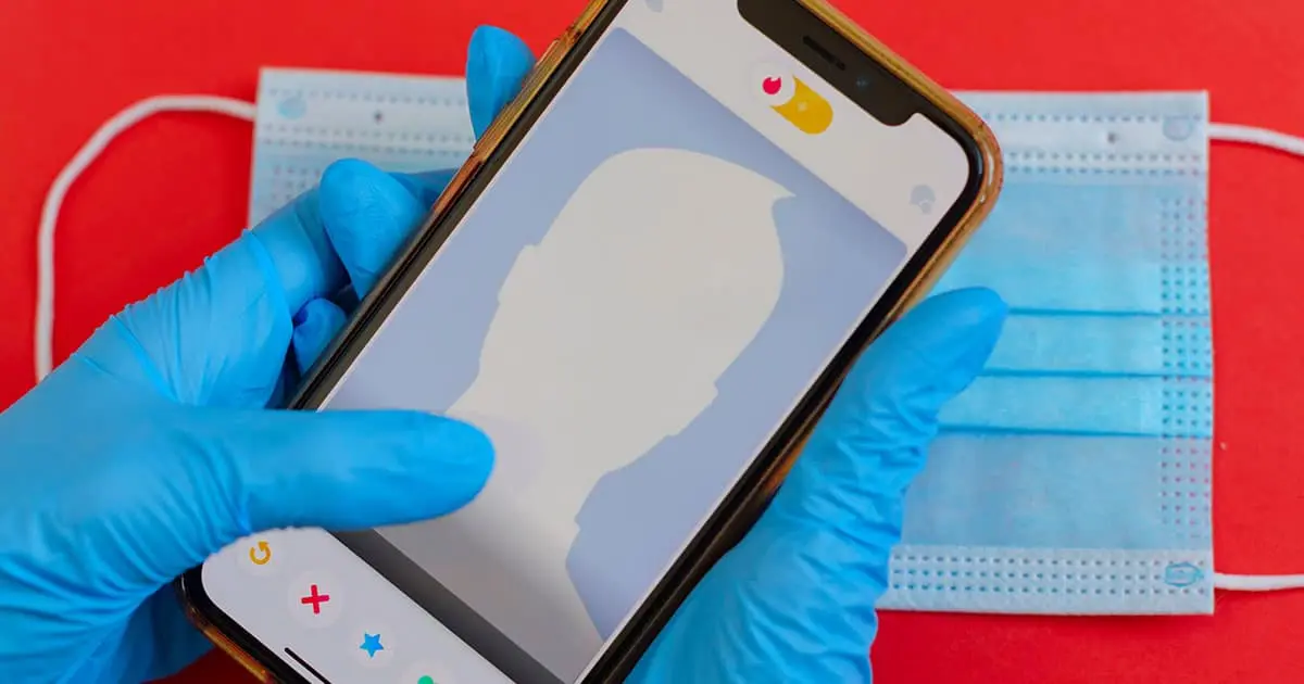 Article suivant : Mains gantées de bleu tenant un smartphone au-dessus de masques chirurgicaux, sur fond rouge